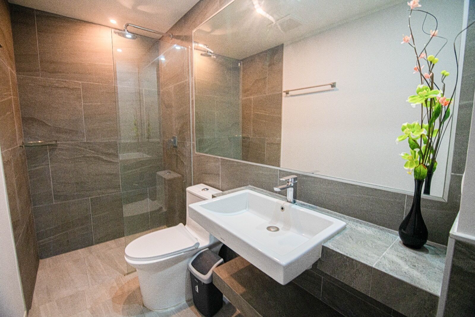 A modern bathroom with a shower, toilet, and sink.