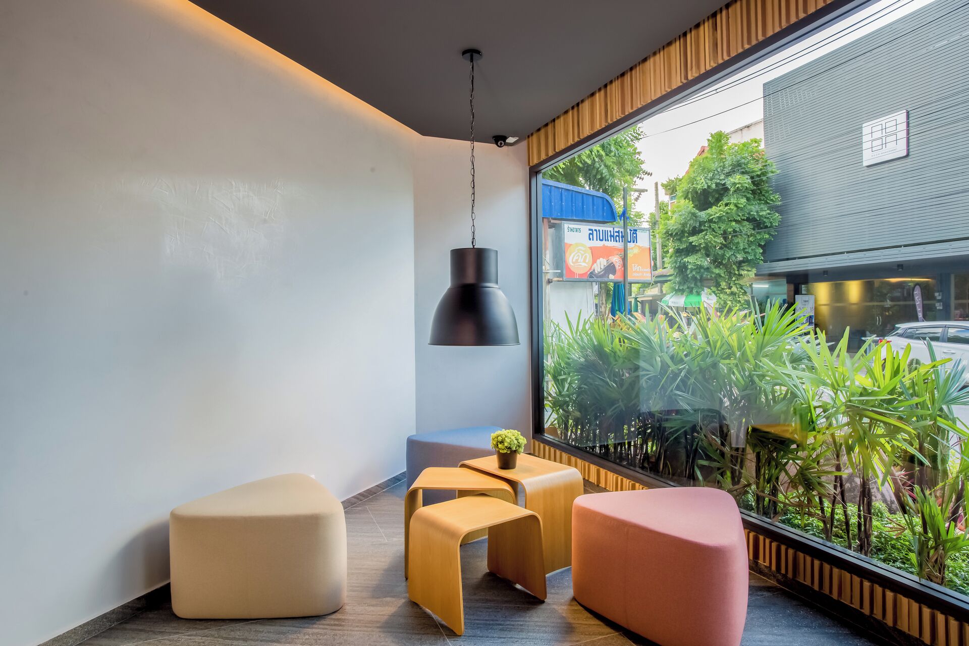 A modern interior with a large window, a hanging pendant light, and a small table with a plant.