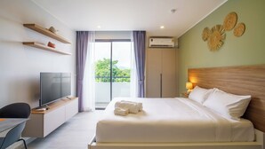 A hotel room with a bed, a TV, a desk, and a balcony with curtains. - Thai me up the Tower (Chalong)
