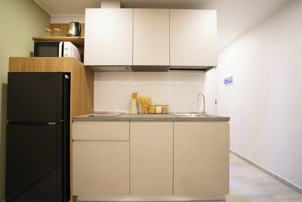 A compact kitchen with a black refrigerator, a microwave, and a sink. - Thai me up the Tower (Chalong)