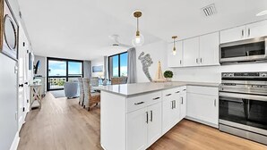 A modern kitchen with white cabinetry, stainless steel appliances, and a large island. - Sundestin 518 (Destin)