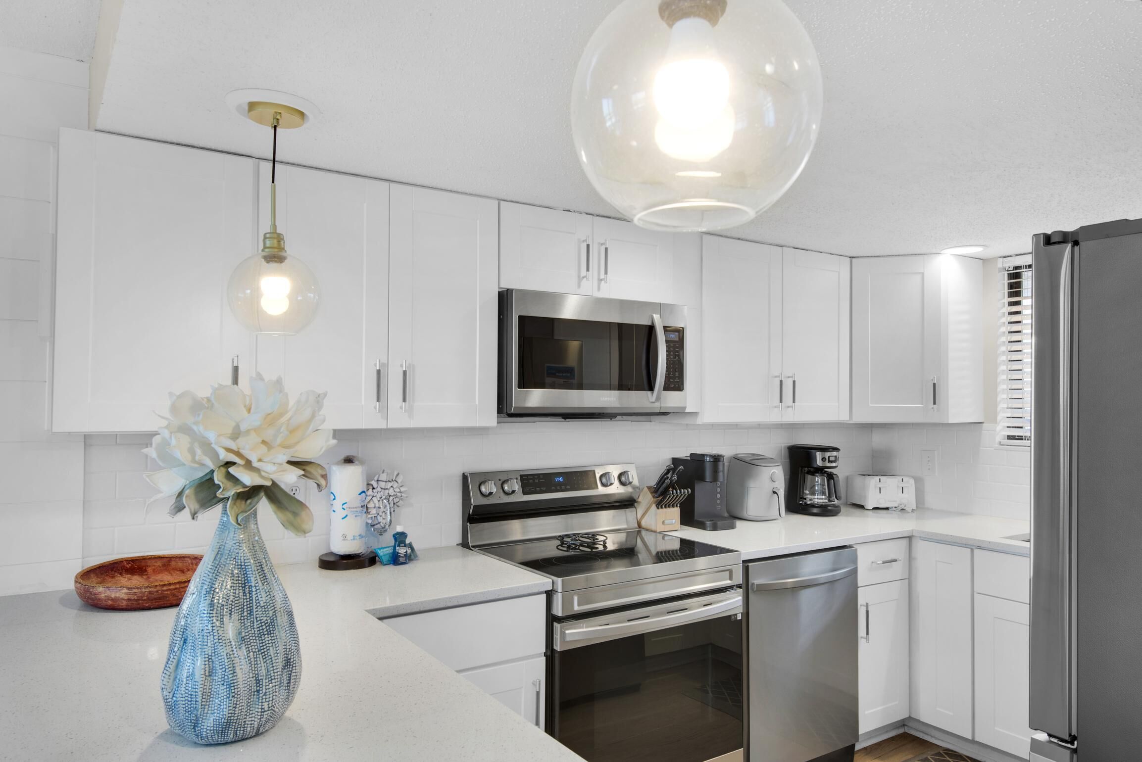A modern kitchen with white cabinets, stainless steel appliances, and a vase with flowers on the counter.