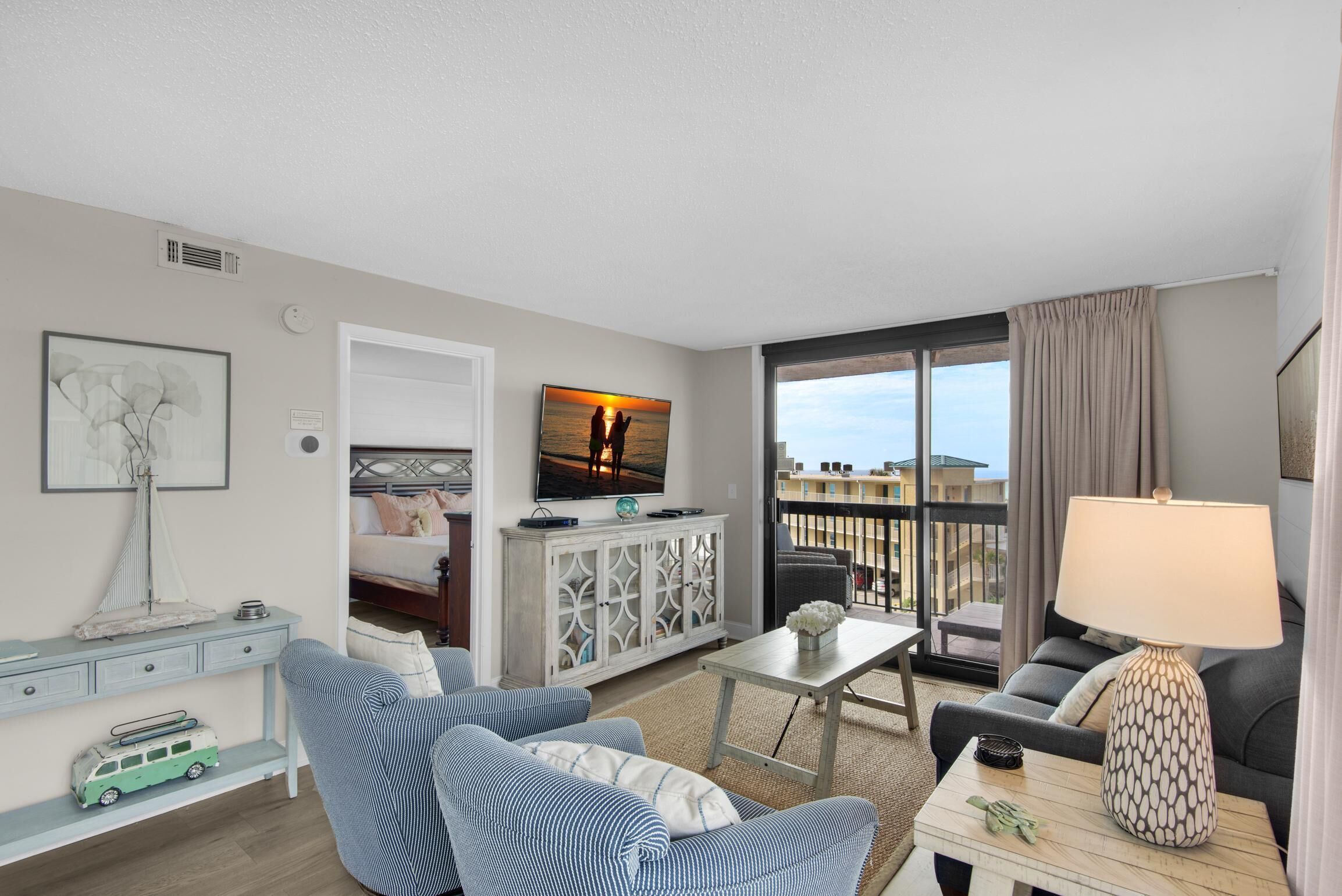 Une chambre d’hôtel moderne dotée d’un balcon, d’une télévision, d’un canapé, d’une table à manger et d’une lampe.