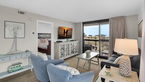 A modern hotel room with a balcony, a television, a sofa, a dining table, and a lamp. - Sundestin 518 (Destin)