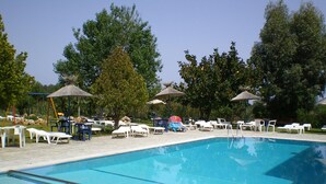A swimming pool with lounge chairs and umbrellas, surrounded by trees. - Celadi vista (Rhodes)