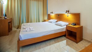 A hotel room with a wooden bed, two bedside tables, a nightstand, a mirror, and a window with curtains. - Celadi vista (Rhodes)