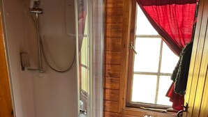 A small, compact bathroom with a glass-enclosed shower, a white toilet, and a window with a red curtain. - Family Cabin Ben Morecrianlarich, West Highland (Crianlarich)