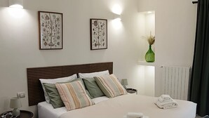 Ein modernes Hotelzimmer mit einem großen Bett, einem Nachttisch mit Lampe und zwei Wandleuchten.