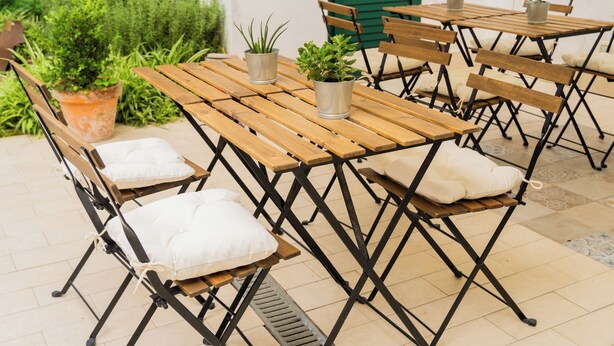Eine Terrasse im Freien mit Holztischen und -bänken, einige mit Kissen.