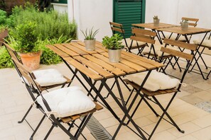 An outdoor patio with wooden tables and benches, some with cushions. - La Puteca  (Naples)