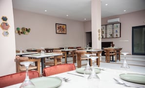 A restaurant with multiple tables set for dining, chairs, and a wall-mounted wine rack. - Hotel KEMAKA (Abidjan)