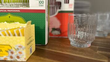 Una caja de bolsitas de té y un vaso sobre una superficie de madera.