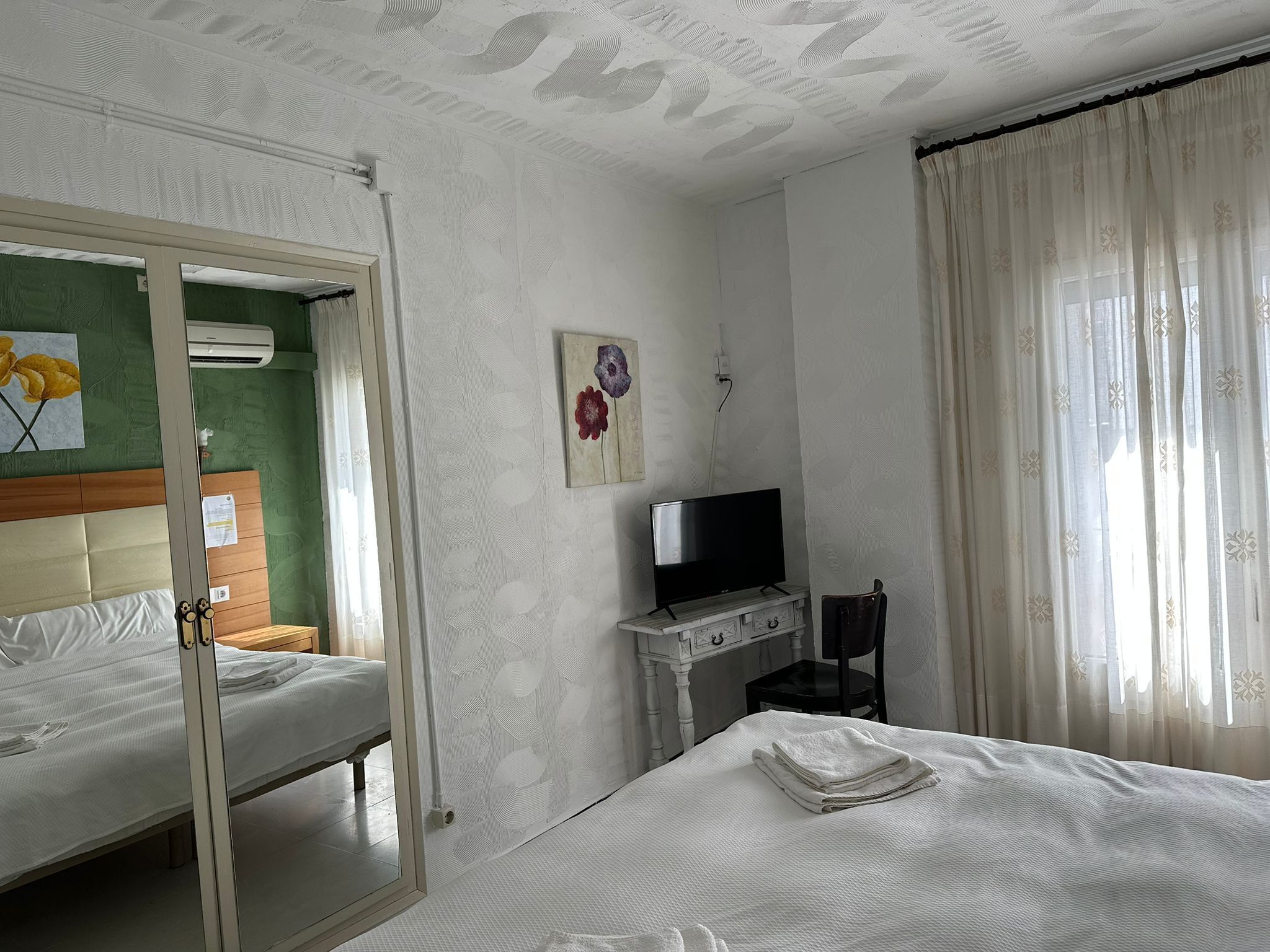 Una camera d'albergo con un letto, una televisione, una scrivania e una sedia.