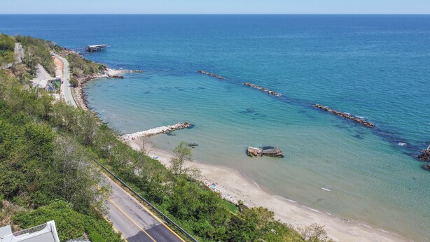 Une route côtière bordée d’une plage et de formations rocheuses.