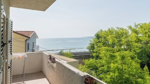 Un balcon avec vue sur la mer, une rambarde en métal et un bâtiment doté d’un toit recouvert de tuiles.