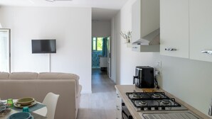 Une cuisine moderne équipée d’une cuisinière à gaz, d’une machine à café et d’un téléviseur à écran plat fixé au mur.