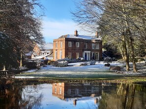 Stroll through the tranquil front yard, surrounded by mature trees and a serene pond.