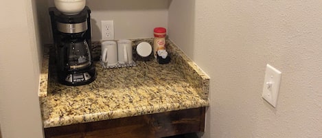 A compact kitchen with a microwave, coffee maker, and a refrigerator.