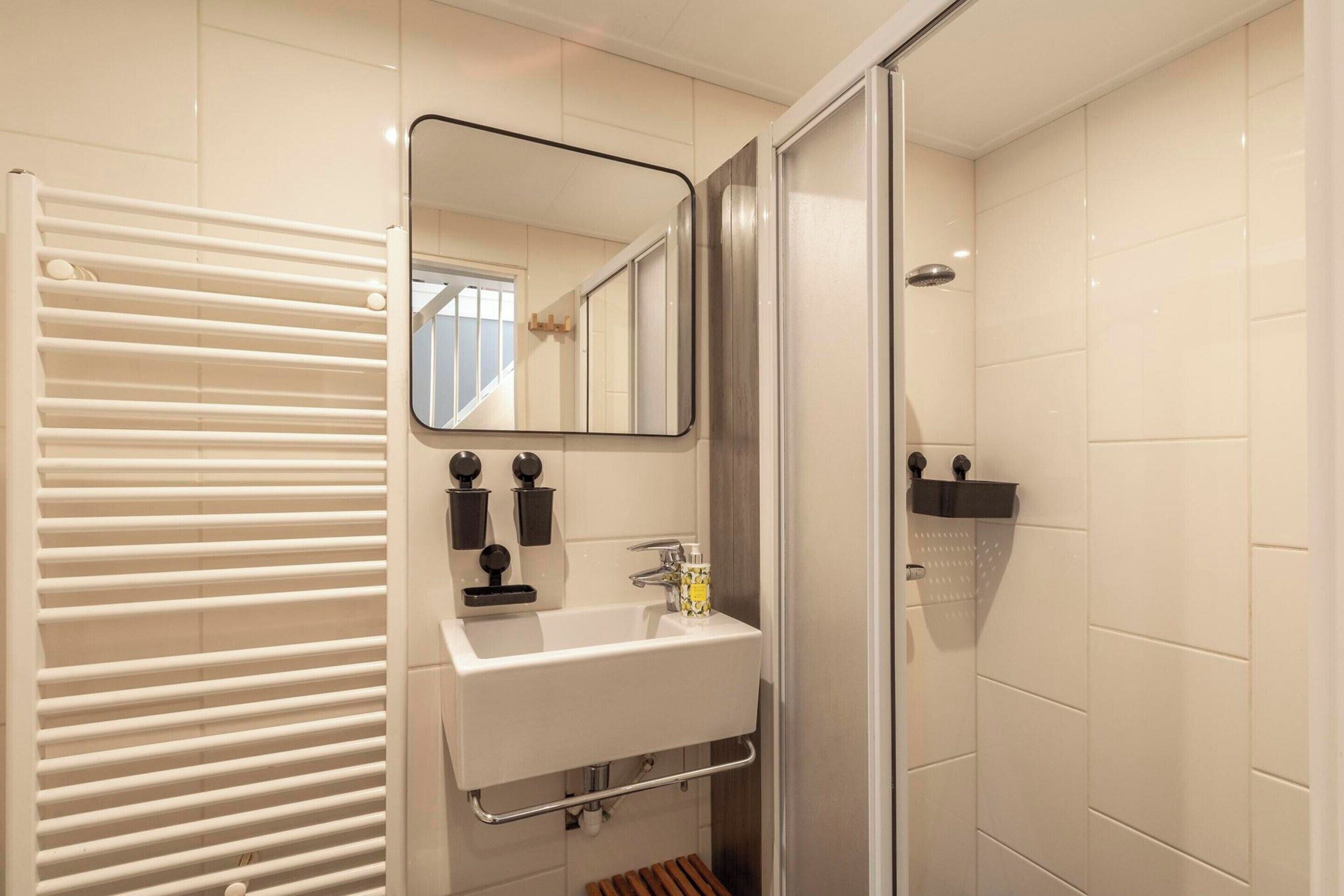 A bathroom with a white sink, a mirror, a shower, and a towel rack.