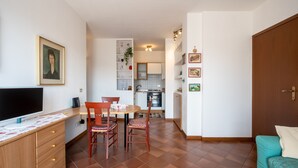 A compact living space with a dining area, kitchenette, and a television on a wooden cabinet. - Apartment with garage near the center of Verona (Verona)