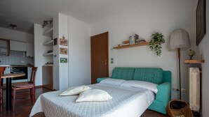 A bedroom with a bed, a chair, a small table, and a shelf with books and a plant. - Apartment with garage near the center of Verona (Verona)