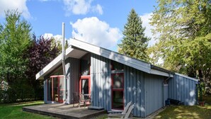Een modern gelijkvloers huis met een overdekte veranda, schoorsteen en klein terras.