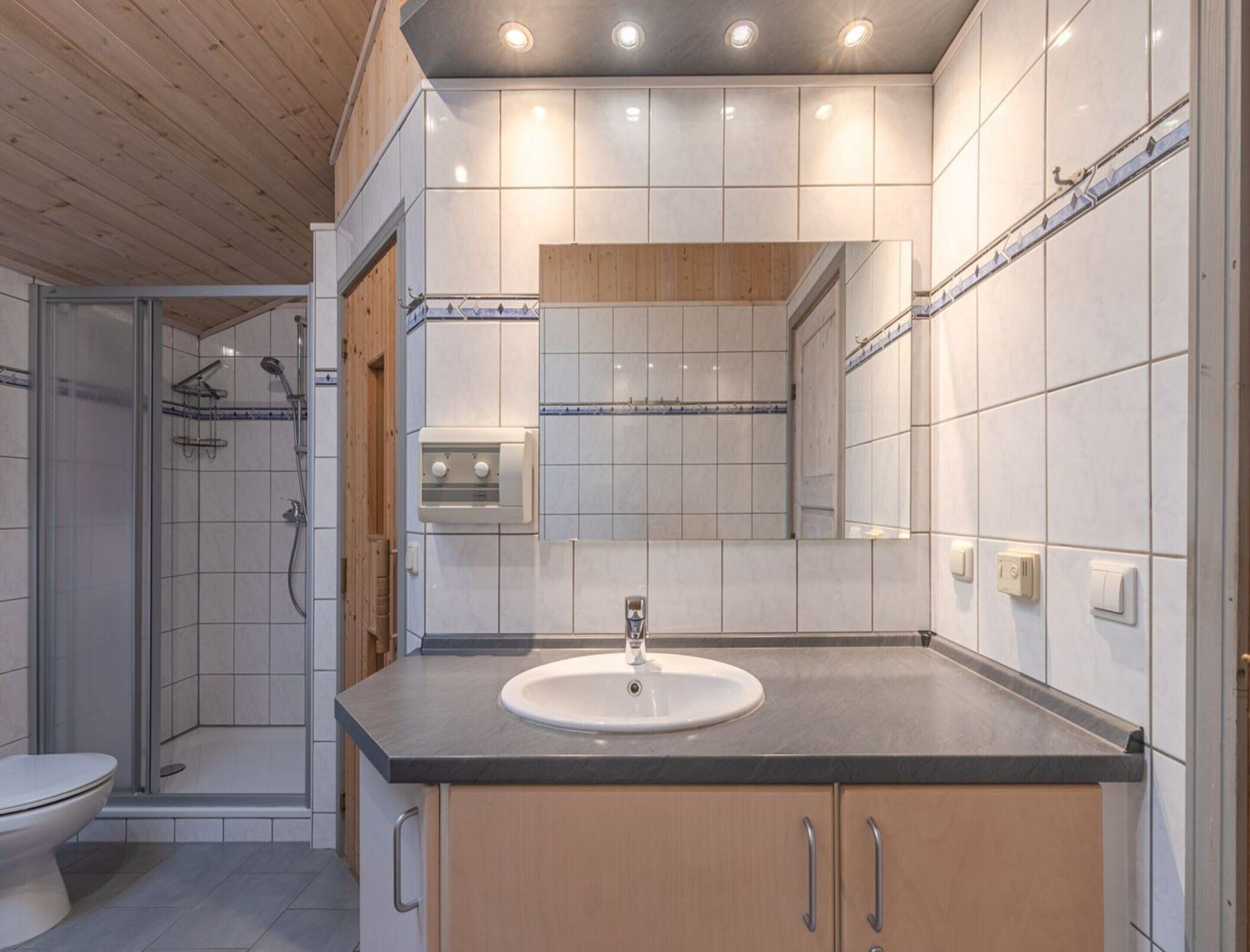 A modern bathroom with a shower, toilet, and sink.