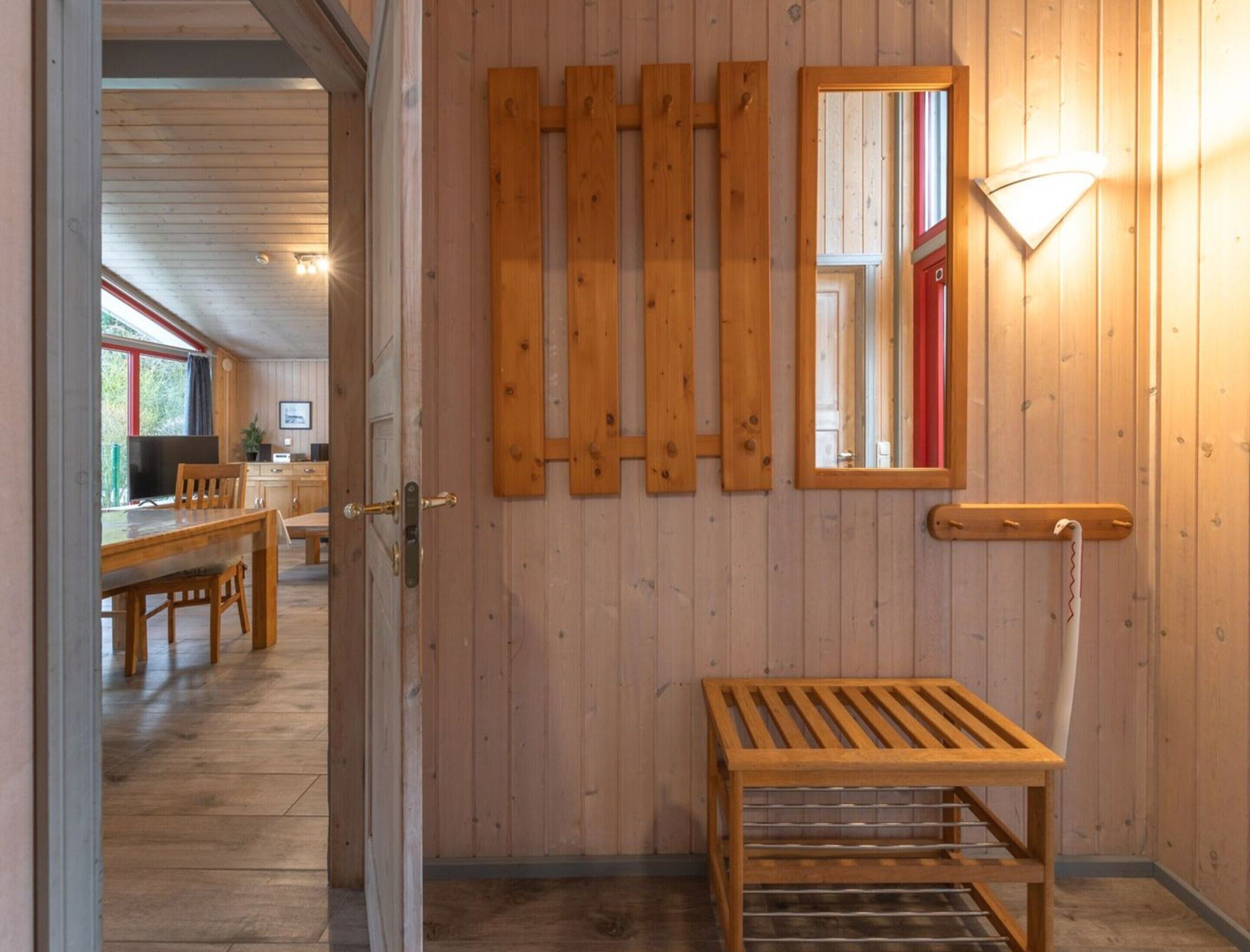 Un intérieur en bois comprenant un coin repas, un banc et un miroir fixé au mur.