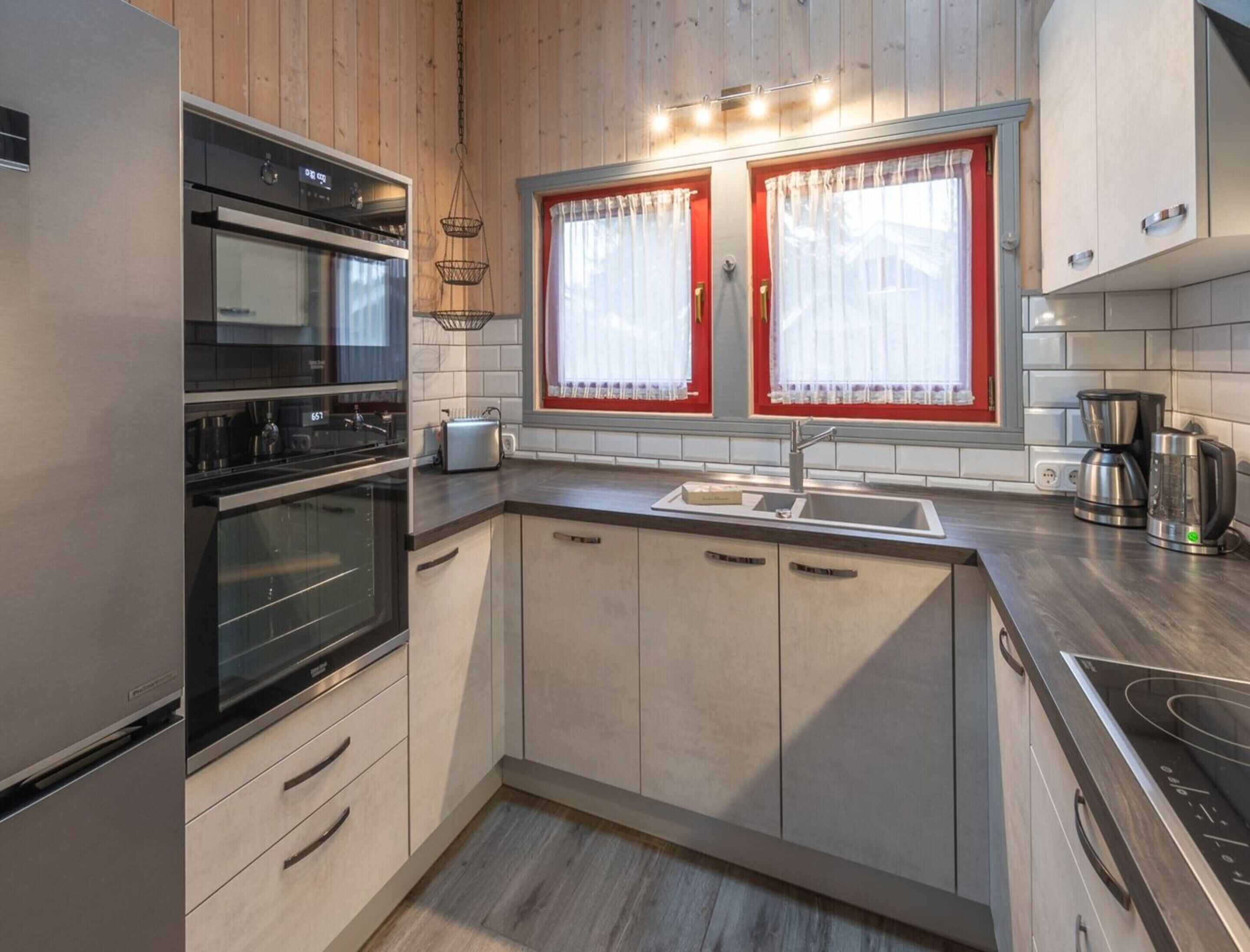 A modern kitchen with wooden cabinets, a double oven, a sink, and a coffee maker.
