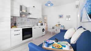 Un apartamento moderno con cocina, comedor y sala de estar. Incluye un sofá, una mesa de comedor y una cocina equipada con microondas y horno.