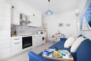 Un apartamento moderno con cocina, comedor y sala de estar. Incluye un sofá, una mesa de comedor y una cocina equipada con microondas y horno.