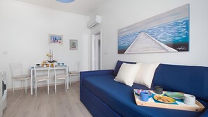 Una habitación moderna con un sofá azul, una mesa de comedor con sillas y un cuadro en la pared.