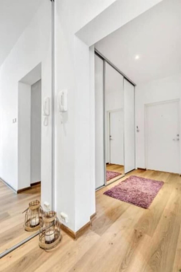 A modern hotel room with a wooden floor, a large mirror, and a pink rug. - Family Friendly, Free Parking Space, Short Walk to Brosundet (Ålesund)