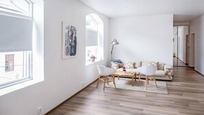 Un vaste espace de vie comprenant un canapé, une table basse et des fauteuils. Une grande fenêtre offre une belle vue sur l’extérieur et permet à la lumière naturelle d’entrer.