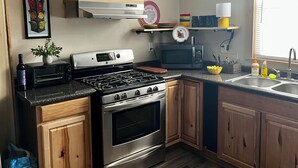 A modern kitchen with stainless steel appliances, wooden cabinets, and a window providing natural light. - Cozy 2-bedroom cabin in charming Lexington with WiFi, AC (Lexington)