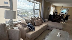 Una sala de estar moderna con un amplio sofá modular, una mesa de centro y un comedor con candelabro.