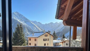 A stone wall and a building with a sloped roof, viewed from a balcony. - [Cogne - Gran Paradiso] Chalet La Grivola (Gimillan)