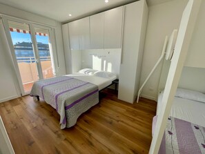 A bedroom with a bed, a window, and a balcony.