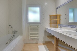 Bathroom features a bathtub, glass-enclosed shower, and a large mirror.