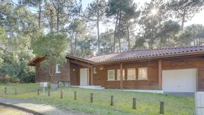 Una cabaña de madera con techo de tejas, garaje y patio cercado.