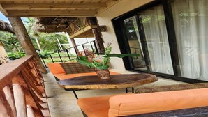 A covered outdoor seating area with orange cushions and a round table, surrounded by wooden railings and a large window. - Charming villa with WiFi and AC, Spa in gorgeous Samaná, 2 minutes from   beach, (Samaná)