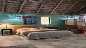 A bedroom with a wooden ceiling, a bed with a white bedspread, a nightstand, a lamp, and a colorful painting on the wall. - Charming villa with WiFi and AC, Spa in gorgeous Samaná, 2 minutes from   beach, (Samaná)