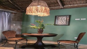 A round table with a woven centerpiece, two wicker chairs, a hanging light fixture, and a framed artwork on the wall. - Charming villa with WiFi and AC, Spa in gorgeous Samaná, 2 minutes from   beach, (Samaná)