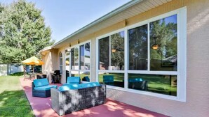 A covered patio with outdoor seating, large windows, and a view of the backyard. - Charming 3-bedroom house in Palm Coast: Near Beach (Palm Coast)
