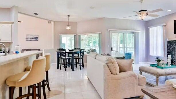 A modern living room with a sofa, coffee table, and bar area with stools. - Charming 3-bedroom house in Palm Coast: Near Beach (Palm Coast)