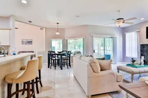 A modern living room with a sofa, coffee table, and bar area with stools.
