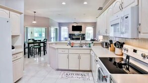 A modern kitchen with white cabinetry, a central island, and a built-in oven. - Charming 3-bedroom house in Palm Coast: Near Beach (Palm Coast)