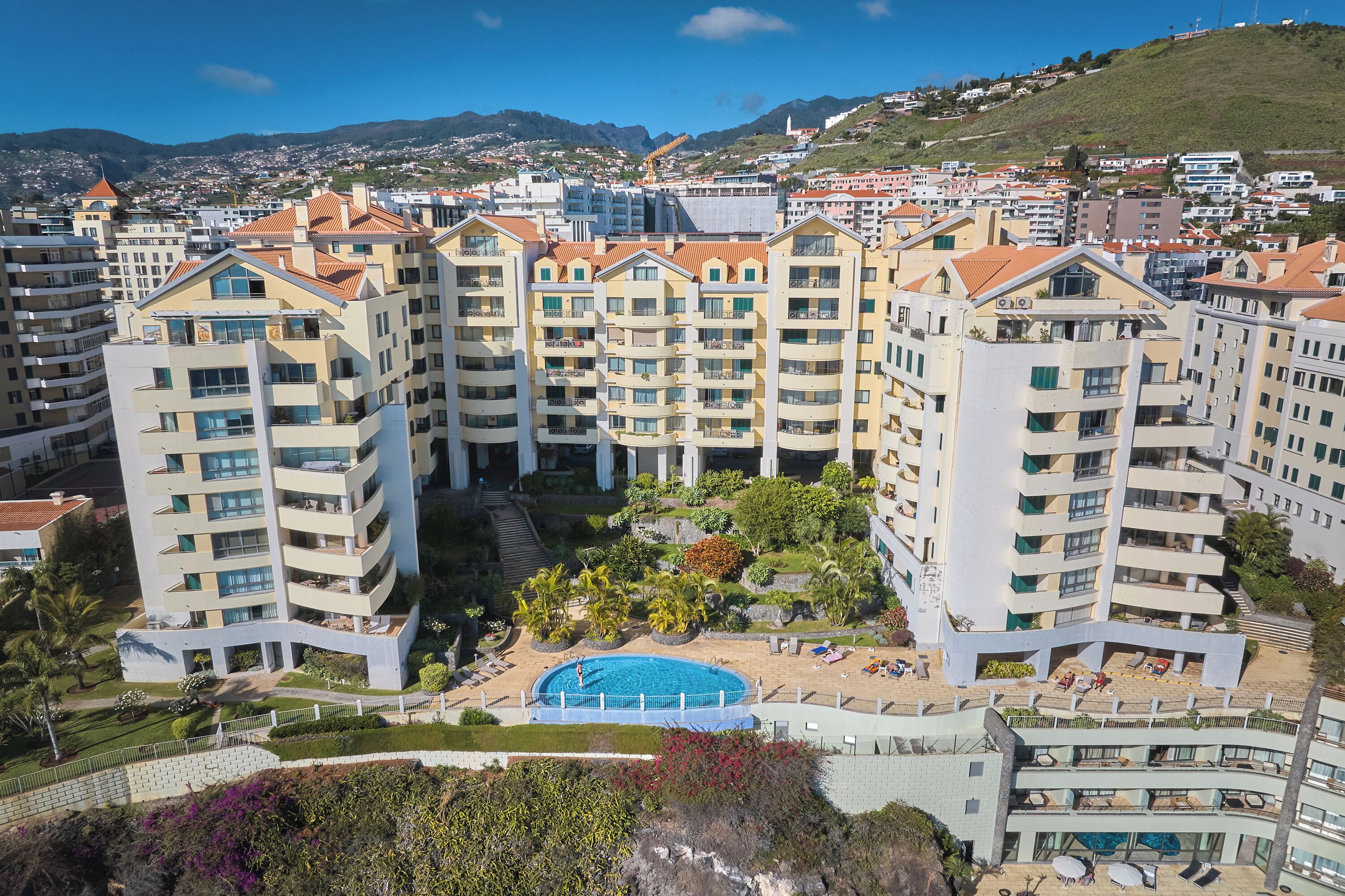 A multi-story residential building with a swimming pool and landscaped gardens.