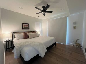 A bedroom with a bed, a ceiling fan, a nightstand, and a wall-mounted deer decoration.
