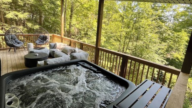 Un bain à remous sur une terrasse en bois, avec vue sur une forêt.